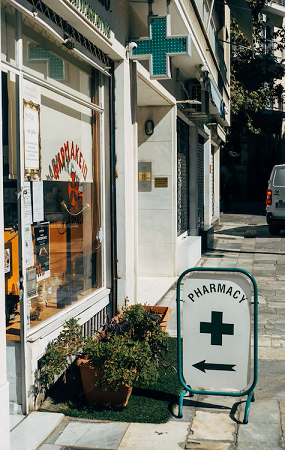 a shopfront with a sign pointing inside with the word "Pharmacy" displayed